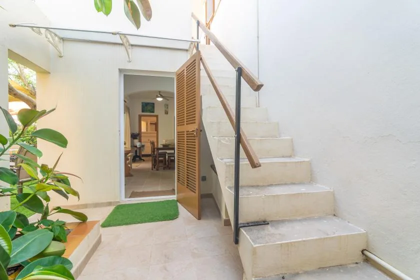 An indoor stairway with a wooden handrail leads to an open doorway.