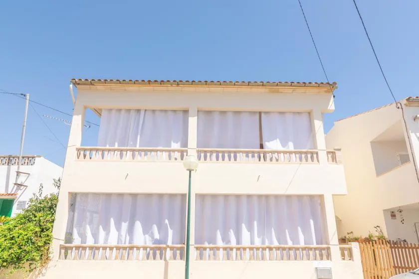A two-story building facade with balconies and white curtains.