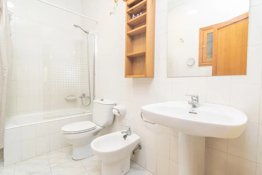 A bright bathroom with a bathtub, toilet, bidet, and wall-mounted sink.