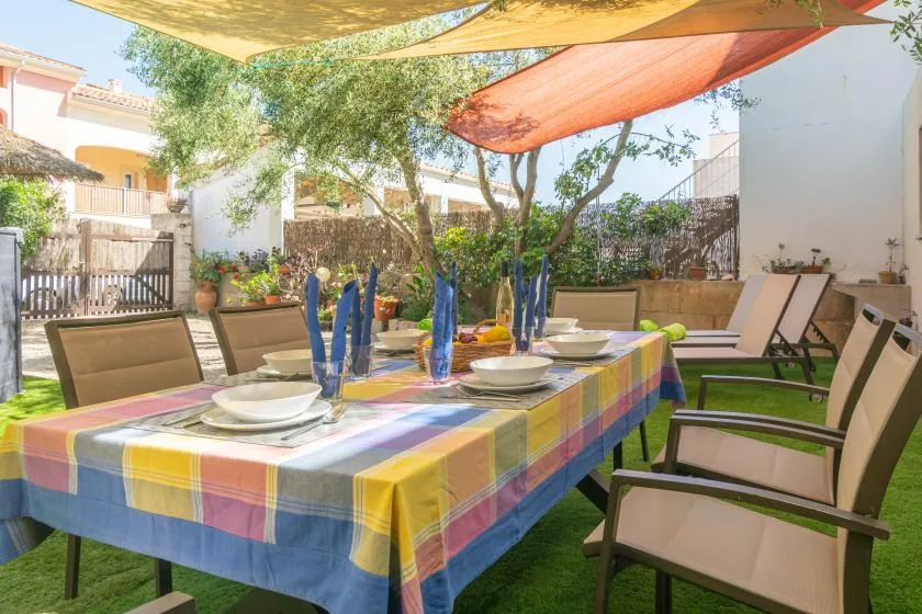 An outdoor dining area with a colorful tablecloth and patio seating under shade sails.
