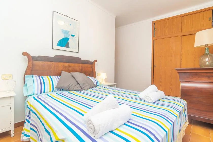 A bedroom with a wooden bed, striped bedding, and folded white towels.