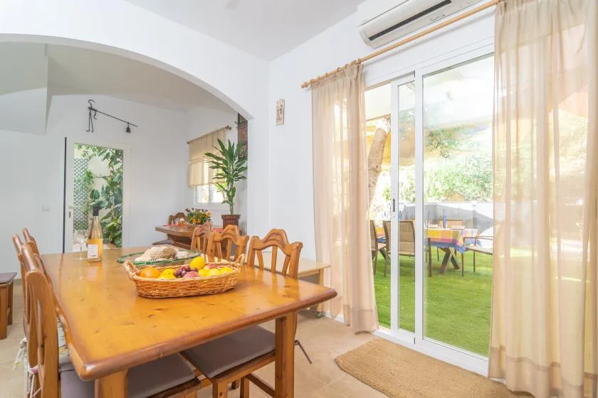 A dining area with a wooden table beside sliding glass doors opening onto a patio.