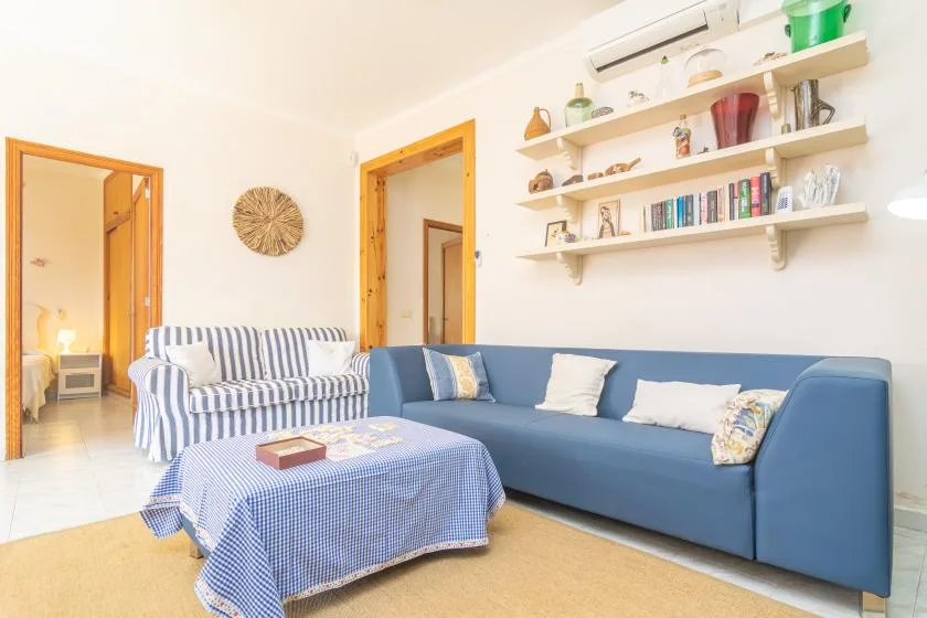 A living room with blue seating, a patterned coffee table, and wall shelves.