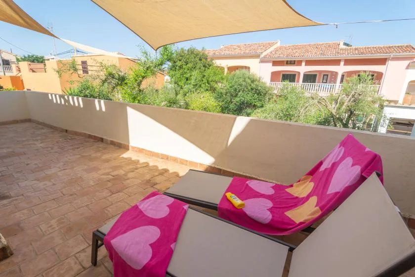 A sunny terrace with a reclining seat beneath a shade canopy.