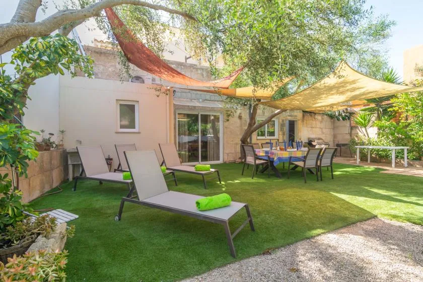 A garden patio with lounge seating, a dining table, and shade canopies.
