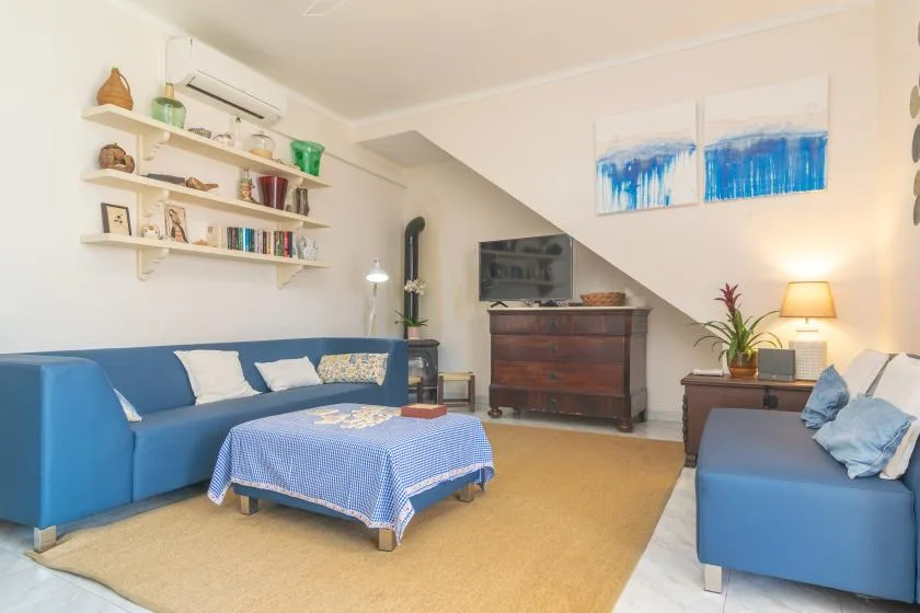 A living room with blue seating, a coffee table, and a television above a wooden cabinet.