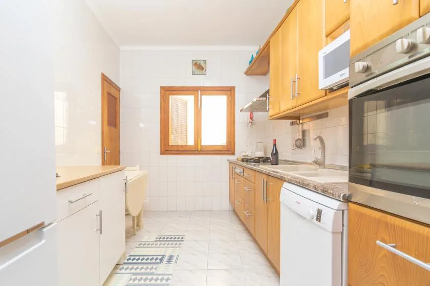 A bright kitchen with wooden cabinets, a countertop, and a window.