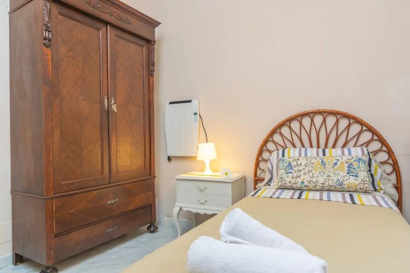 A bedroom with a made bed and a large wooden wardrobe.