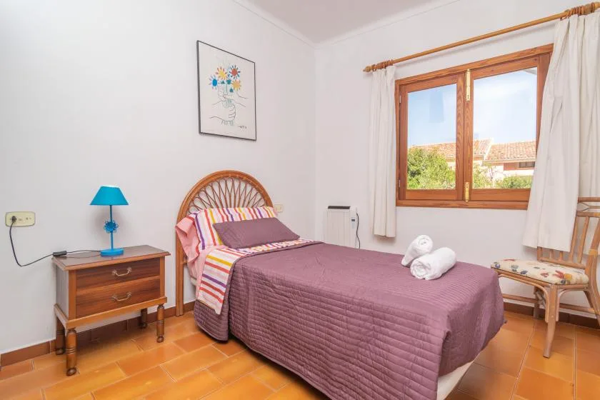 A bedroom with a bed, bedside table, and a window with curtains.
