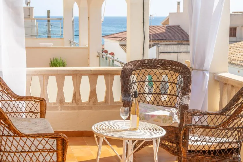 A seaside balcony with wicker seating and views of the ocean.