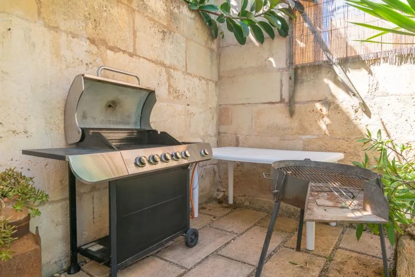 An outdoor cooking area with a barbecue grill and a small table.