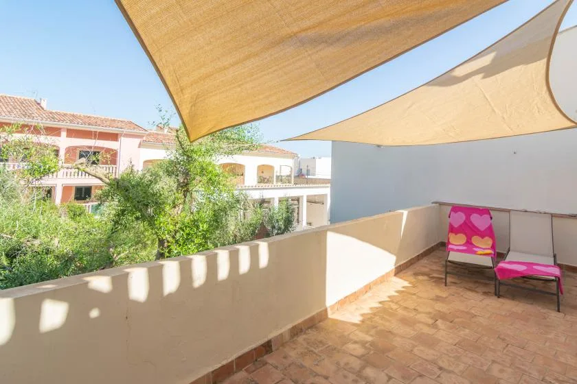 A sunny terrace with fabric shade canopies and colorful seating.