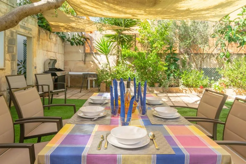 An outdoor dining table sits beneath a canopy in a leafy patio.