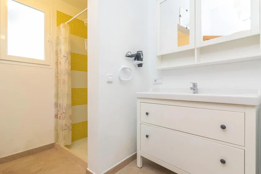 A bright bathroom with a vanity, wall mirror, and shower.