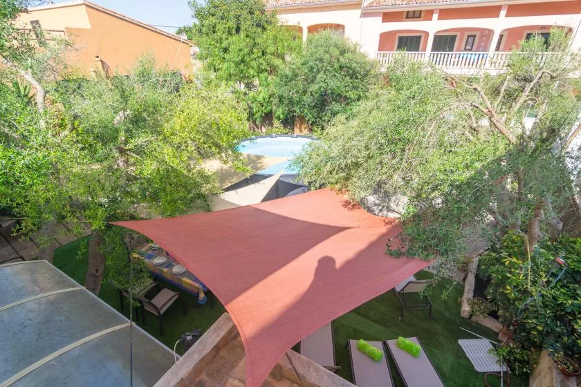 A garden courtyard with a shaded seating area and a small pool beyond the trees.