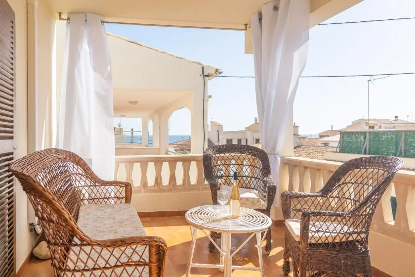 A sunlit balcony seating area with wicker chairs and a small round table.