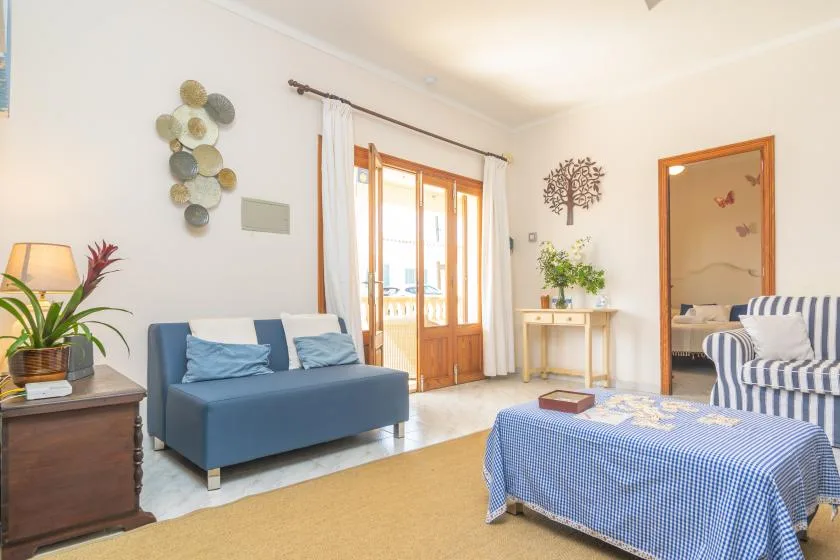A bright living room with blue seating and glass doors opening to a balcony.