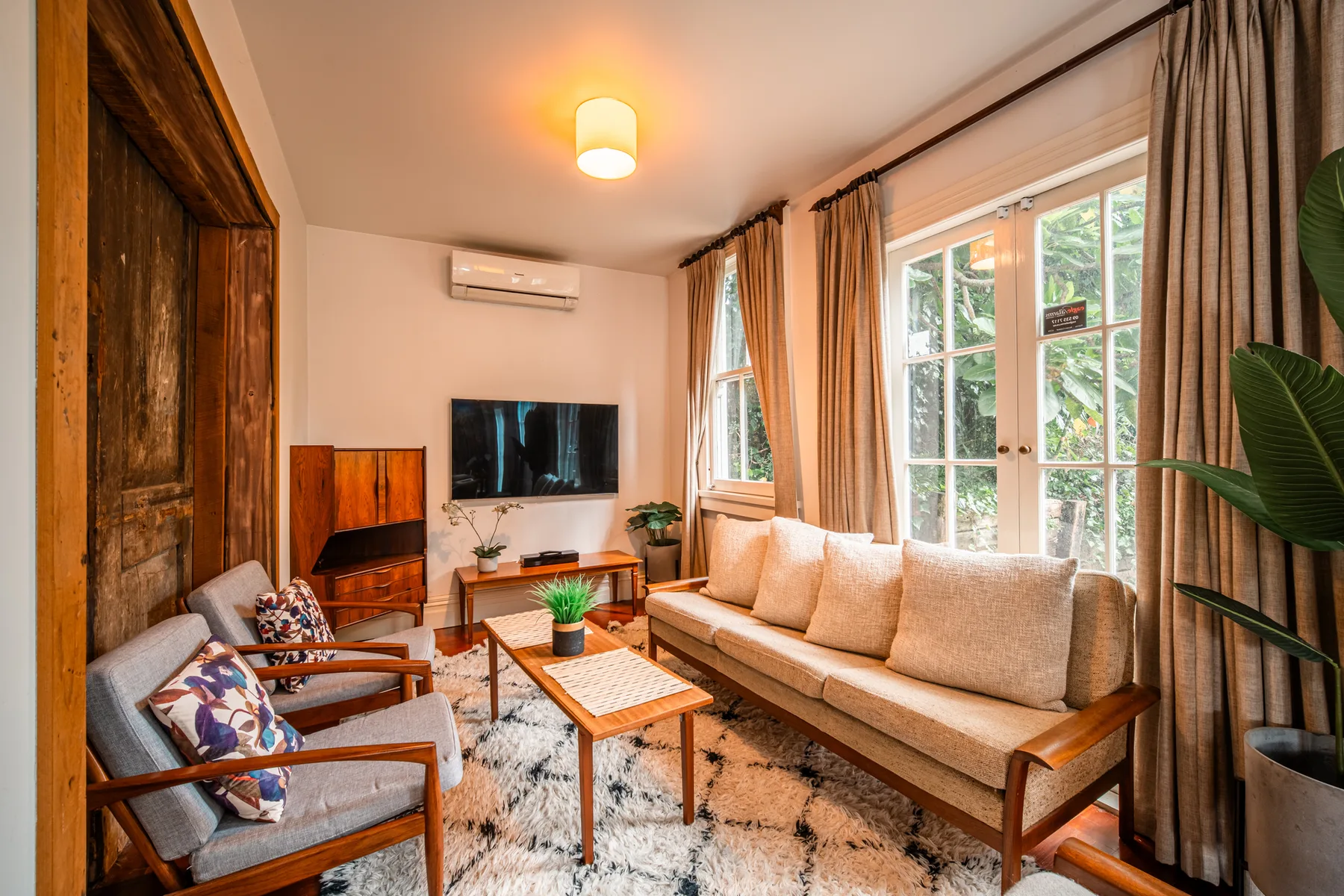 A living room with seating, a coffee table, and large curtained windows.