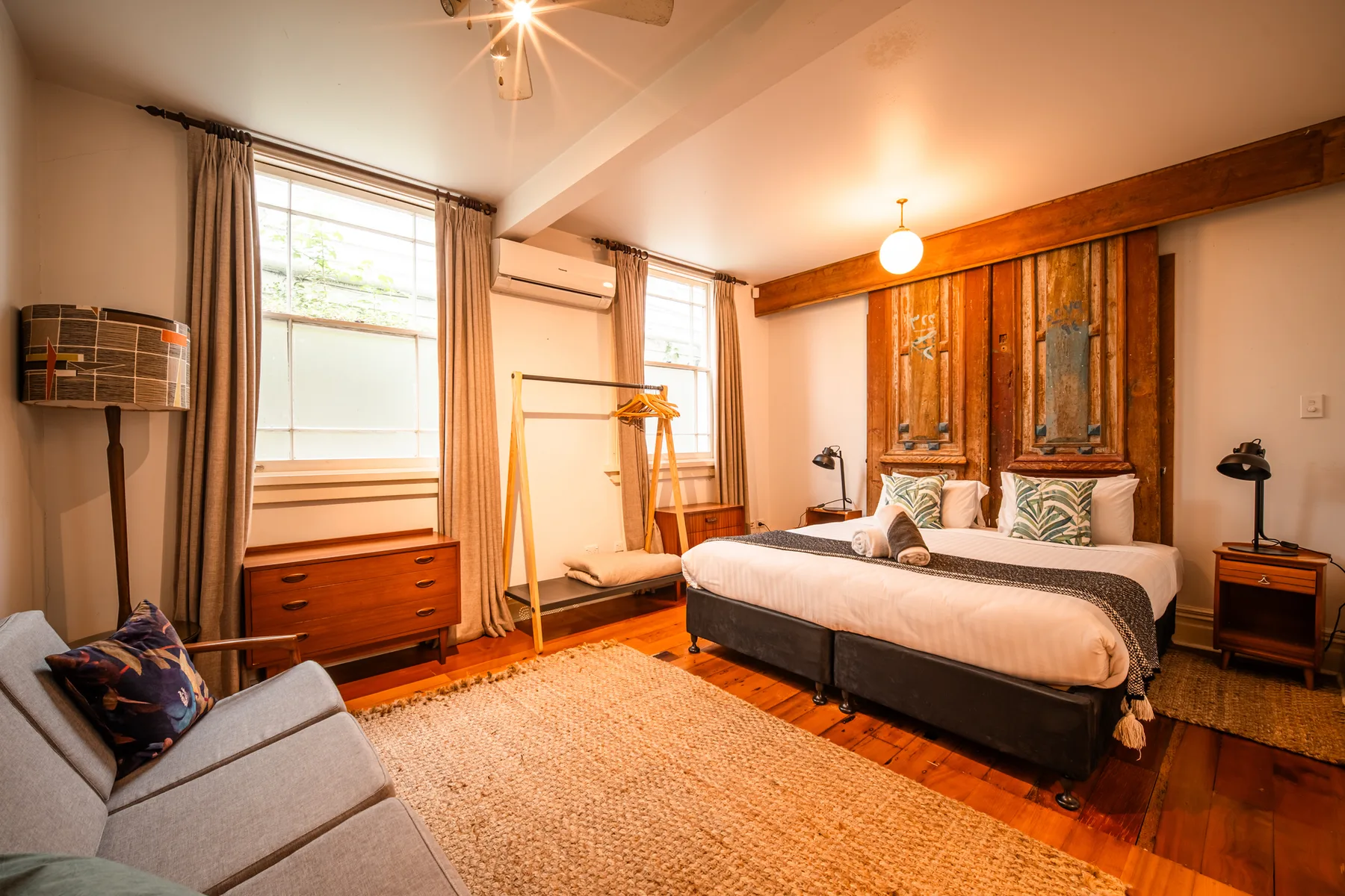 A bedroom with a large bed, wooden wall panels, and a rug.