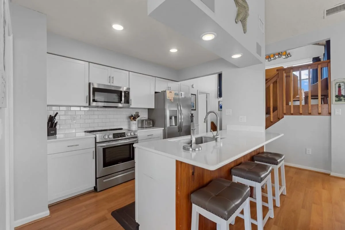 A bright kitchen with white cabinetry, stainless steel appliances, and a central island.