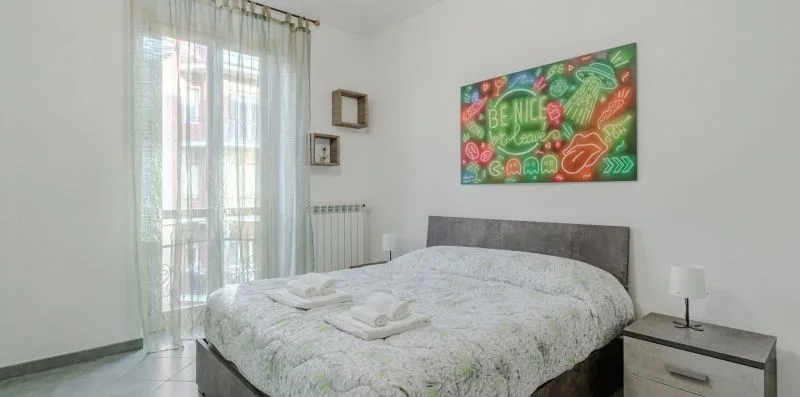 Un dormitorio con una cama, una mesita de noche y arte colorido en la pared.