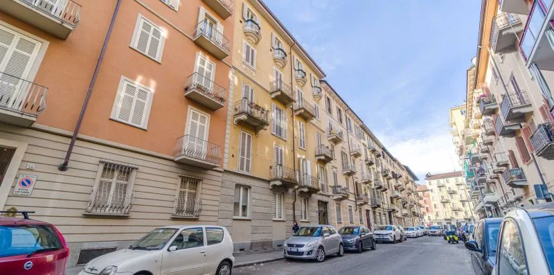 Una calle urbana flanqueada por edificios de apartamentos y coches aparcados.