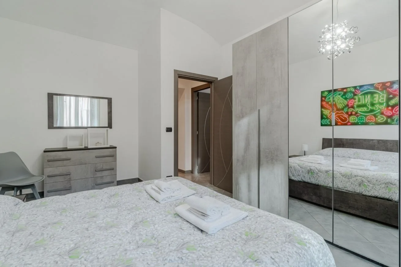 Un dormitorio luminoso con una colcha estampada y puertas de armario con espejo.