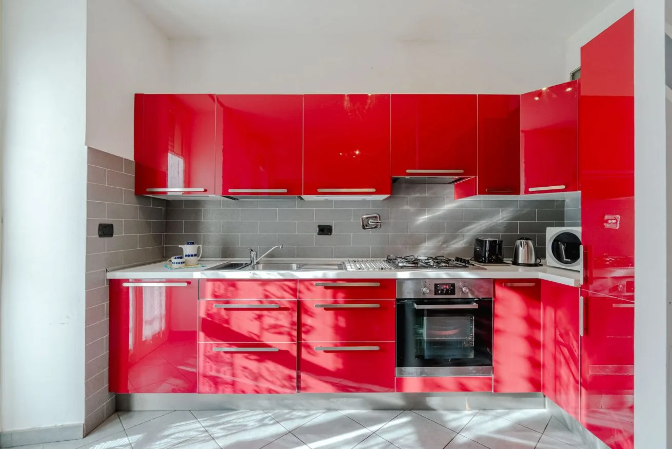 Una cocina moderna con gabinetes rojos brillantes y un horno empotrado.