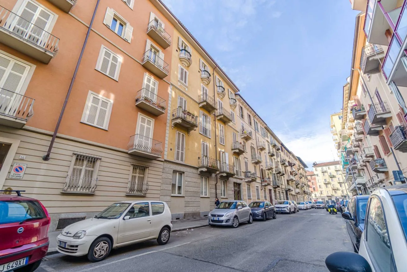 Una calle urbana bordeada de edificios de apartamentos y coches aparcados.