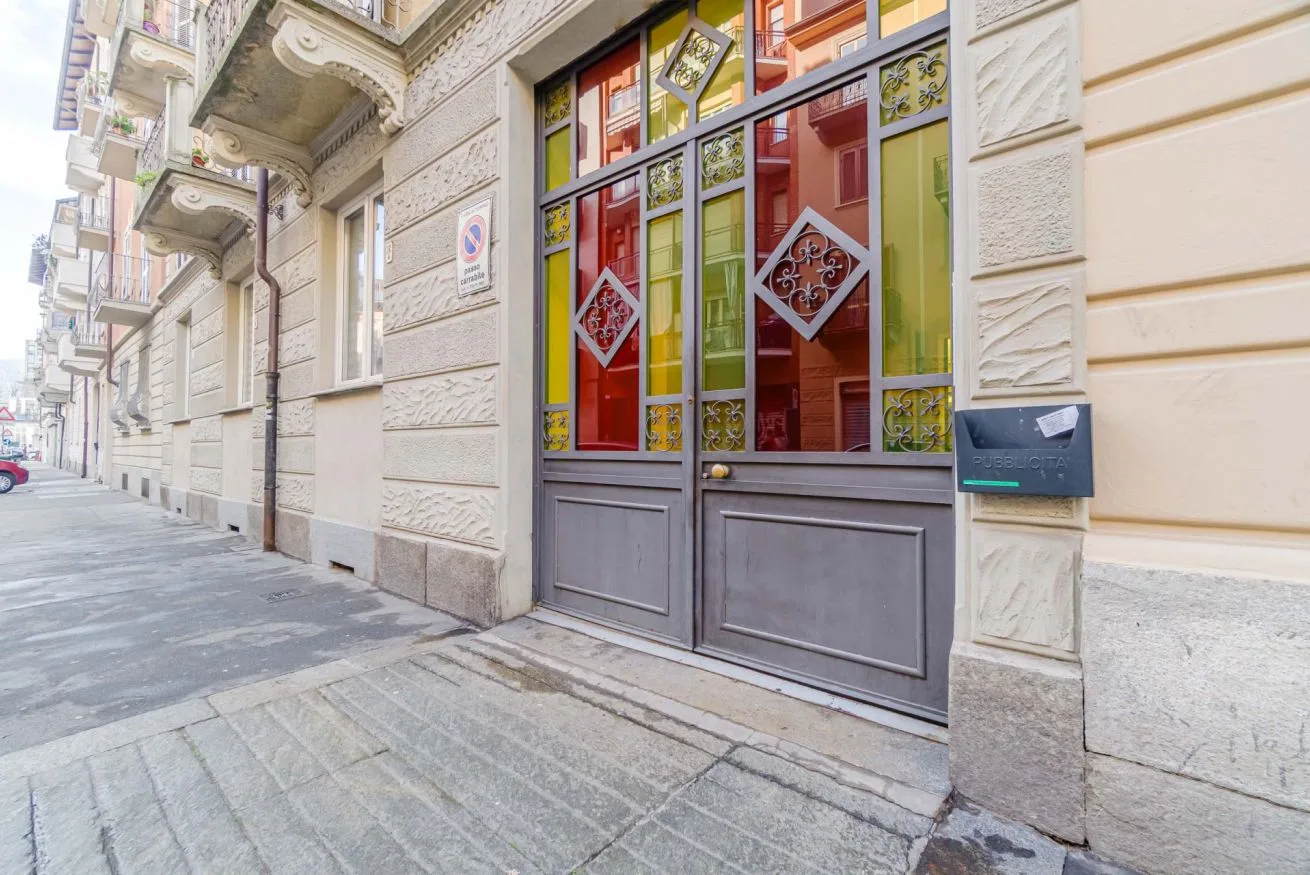 Entrada a nivel de calle con paneles de vidrio coloridos y un buzón.