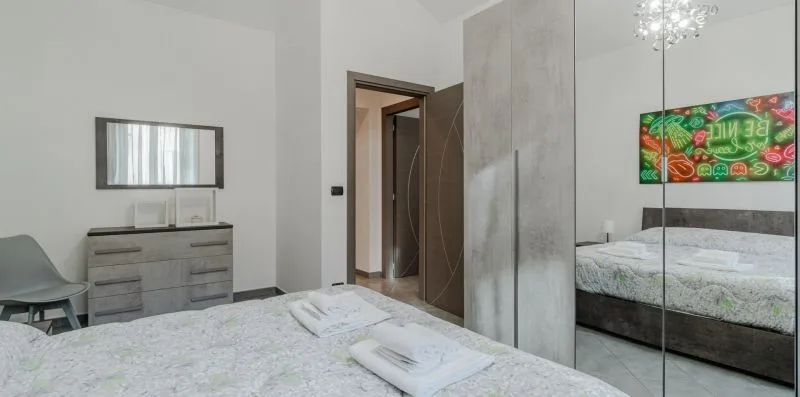 Un dormitorio con cama, toallas dobladas, cómoda y puertas de armario con espejo.