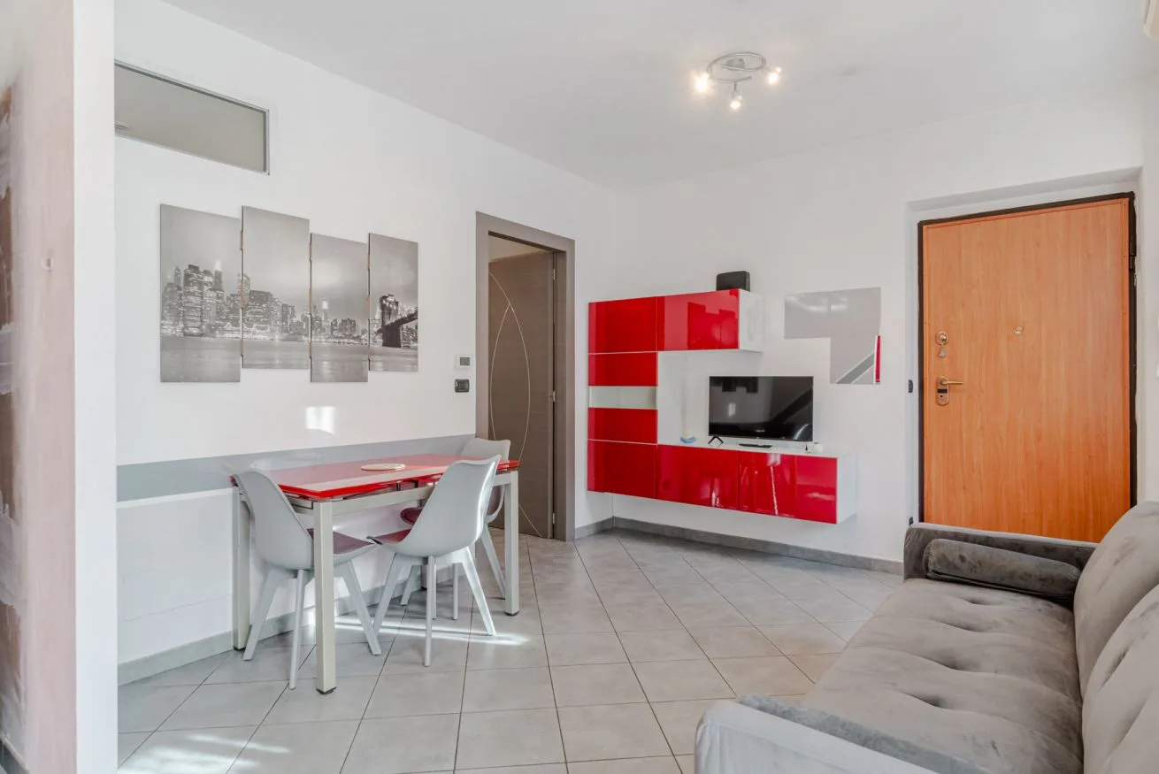 Una luminosa sala de estar con mesa de comedor, asientos y un televisor en la pared.