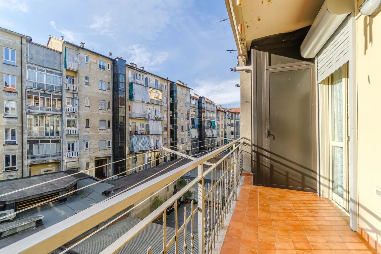 Un balcón embaldosado da a una calle flanqueada por edificios de apartamentos.