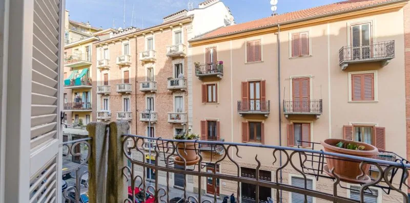 Un balcón da a edificios de apartamentos cercanos con ventanas con persianas y balcones pequeños.