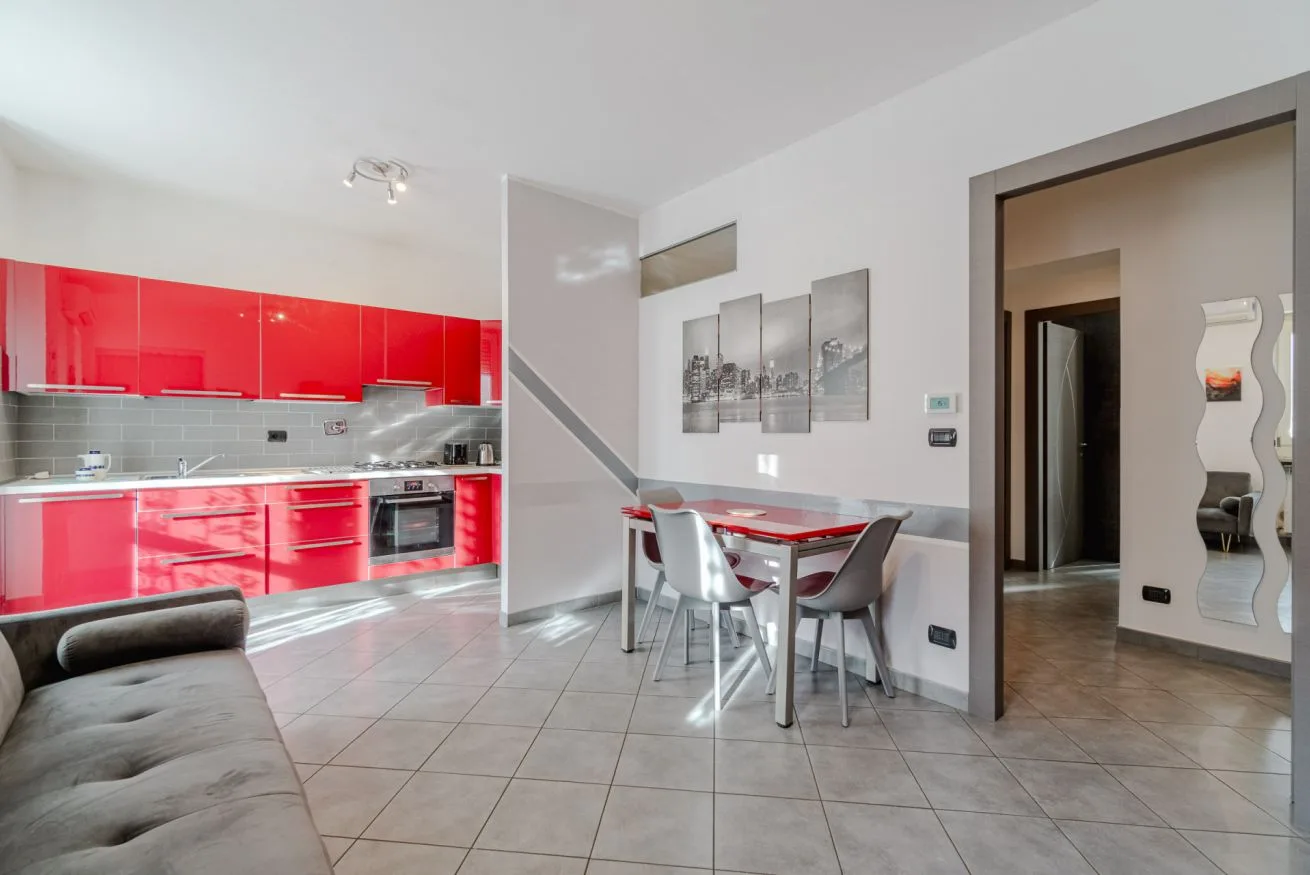 Una cocina y comedor luminosos con gabinetes rojos y una mesa.