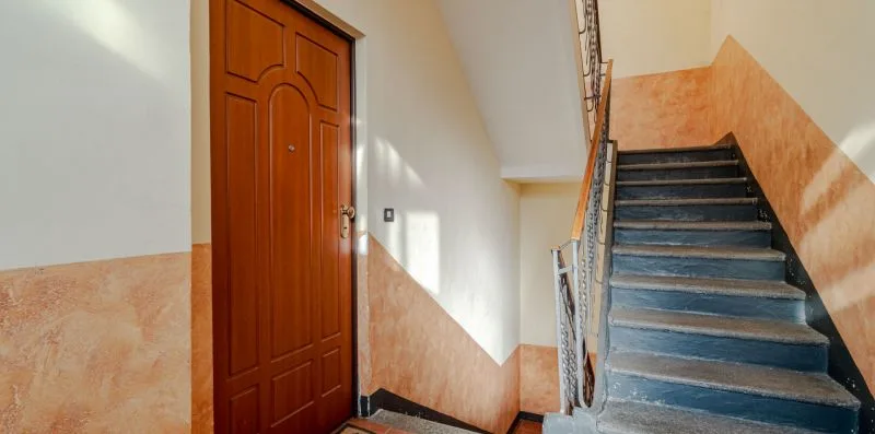 Una escalera interior con una puerta de entrada de madera y peldaños.