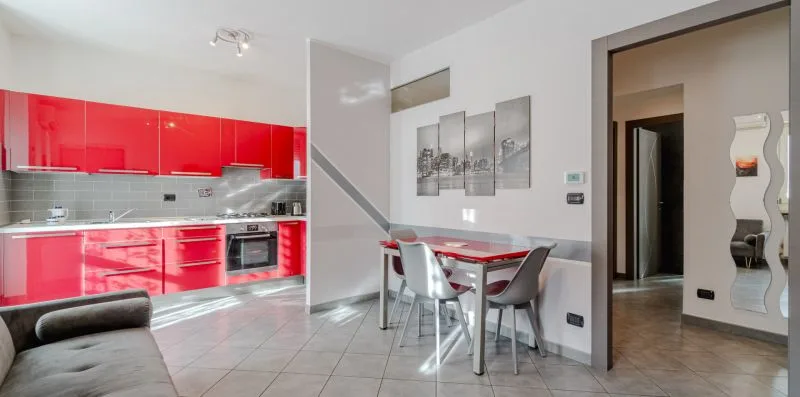 Un comedor con mesa y sillas junto a una cocina de color rojo intenso.
