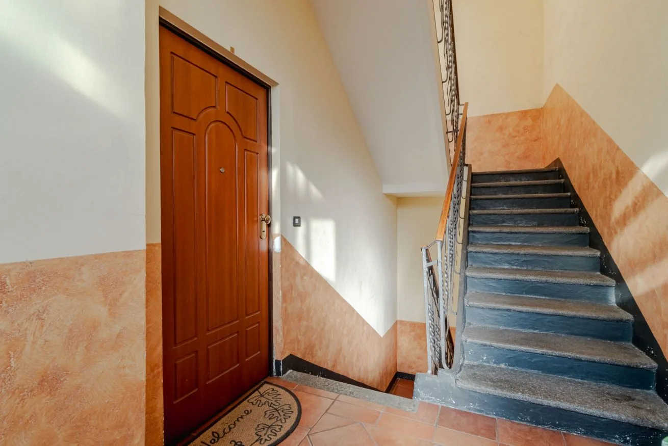 Un recibidor interior con una puerta de madera junto a una escalera.
