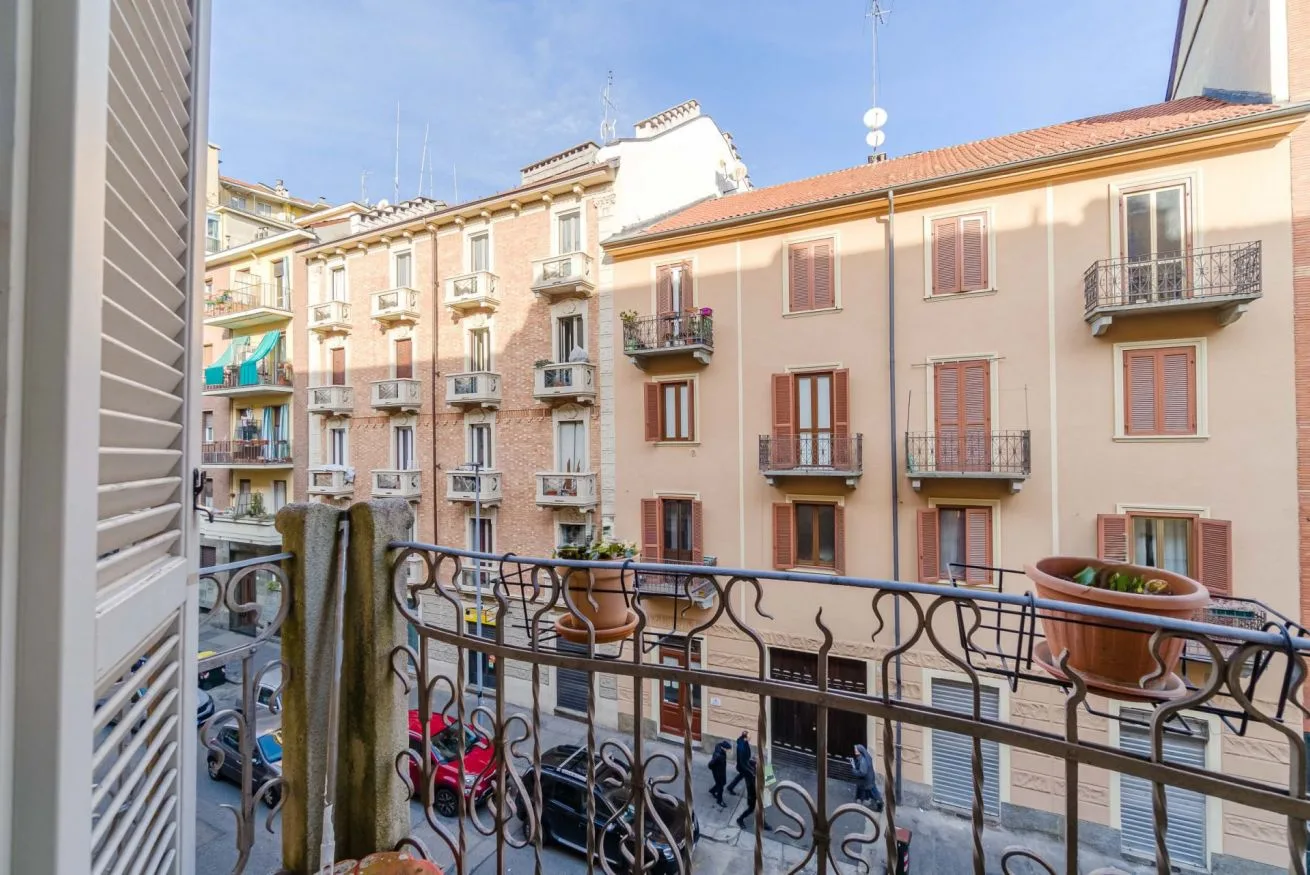 Un balcón da a edificios de apartamentos vecinos en una calle urbana soleada.