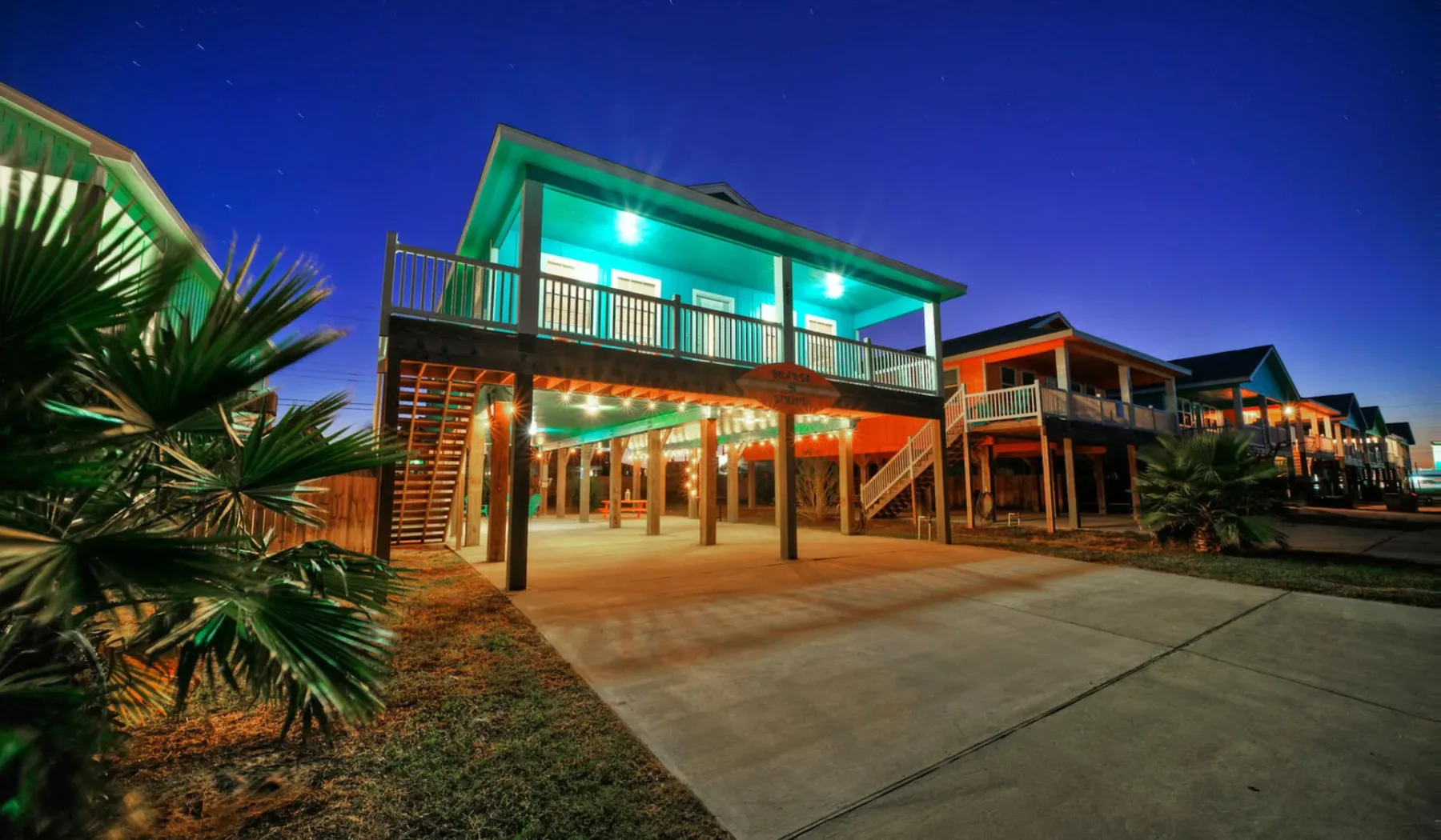 Elevated buildings with balconies line a paved walkway at dusk.