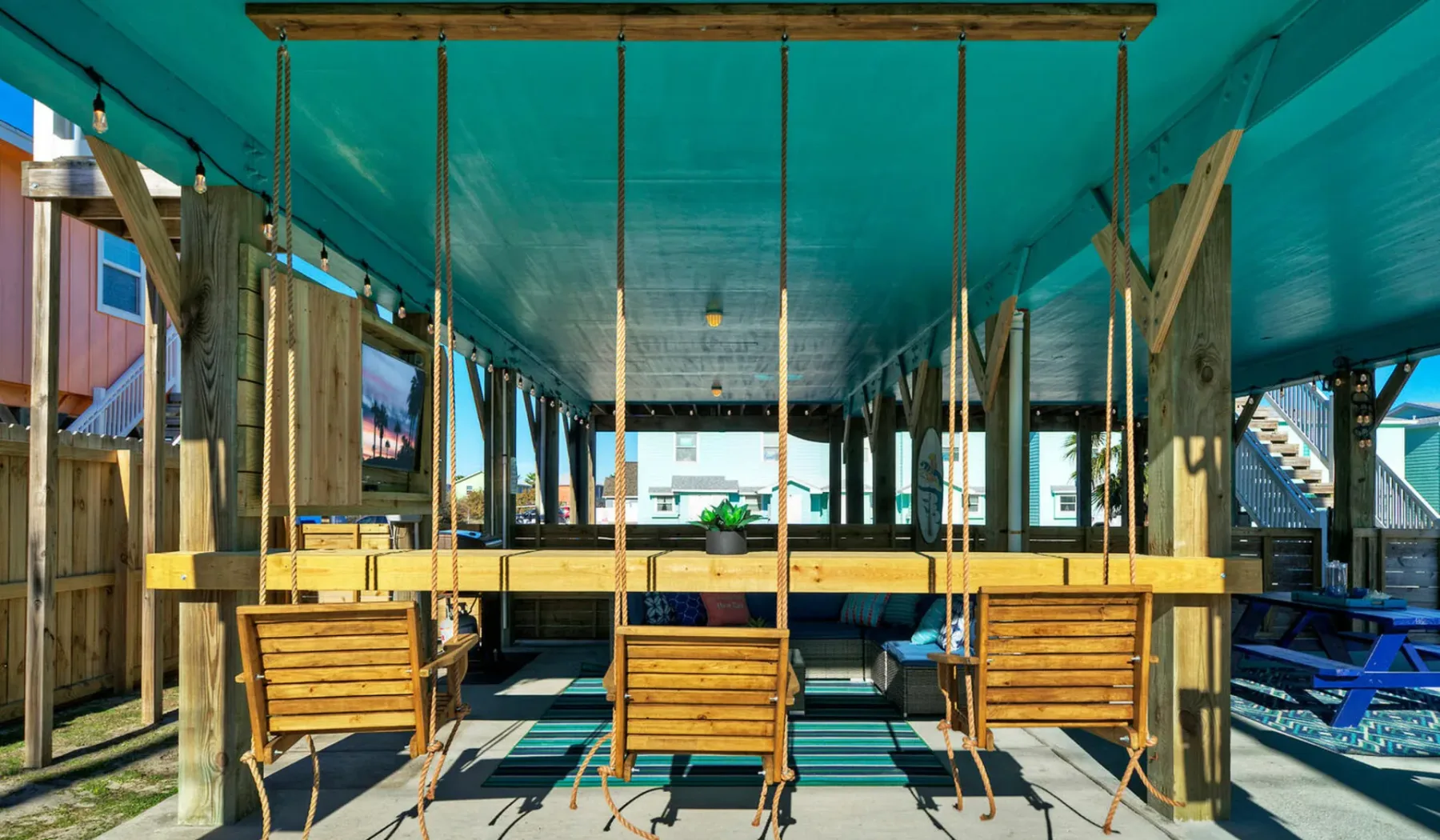 A shaded outdoor seating area with wooden benches beneath a teal canopy.