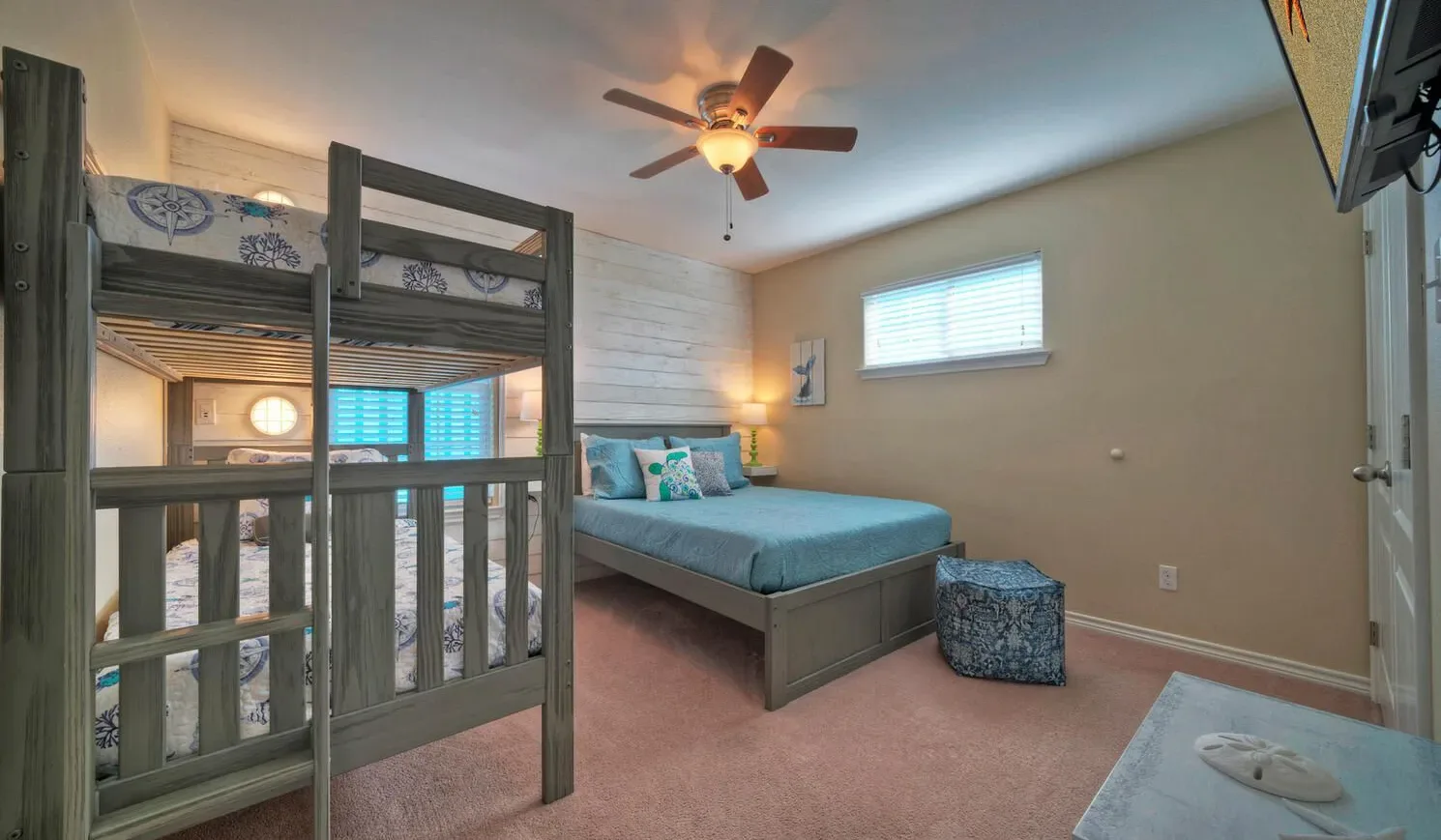A bedroom with bunk beds, a lower bed, and a ceiling fan.