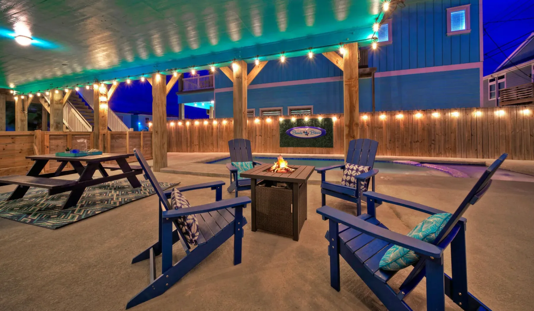 A covered outdoor patio with seating around a fire pit.