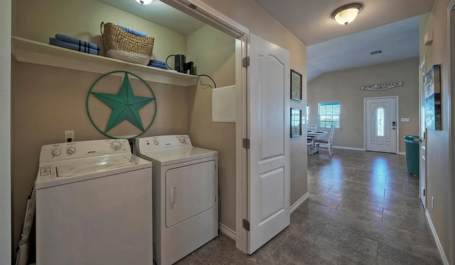 A laundry area with a washer and dryer opens onto a tiled entryway.