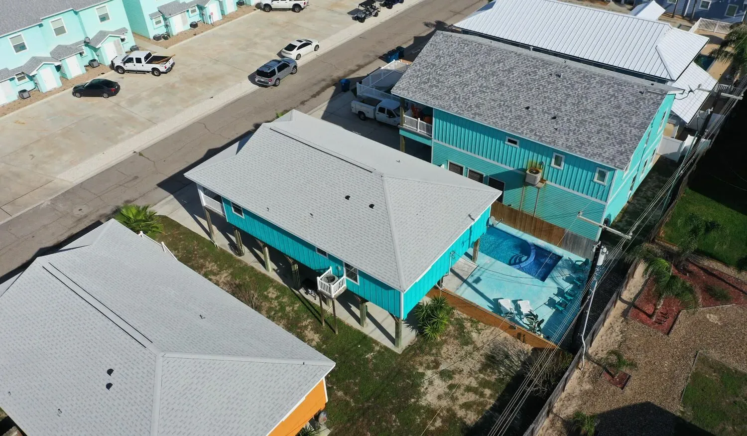 An aerial view shows several turquoise buildings with light-colored roofs.