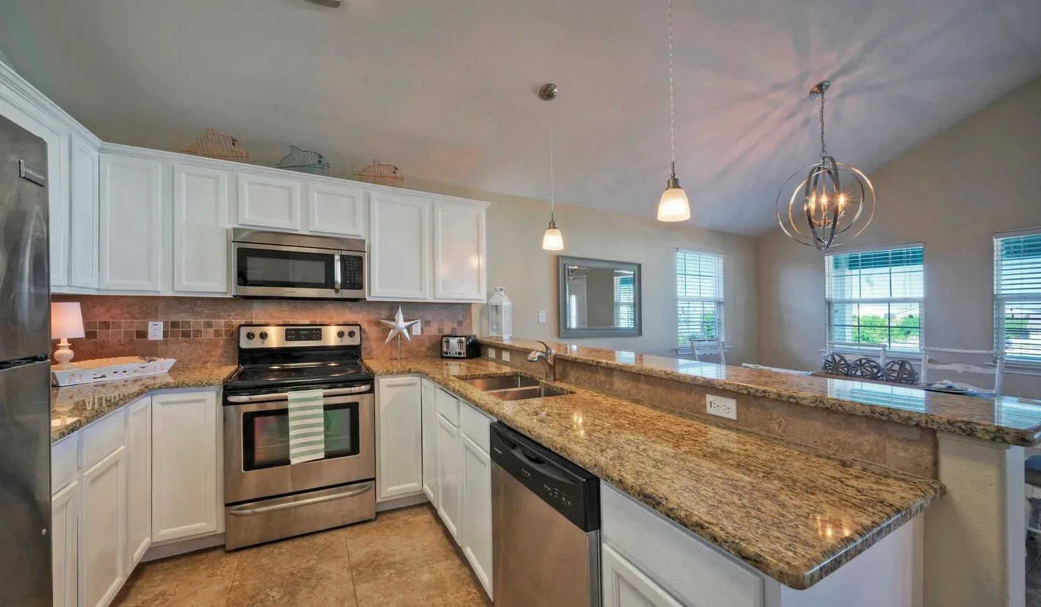 A bright kitchen with white cabinets and granite countertops.