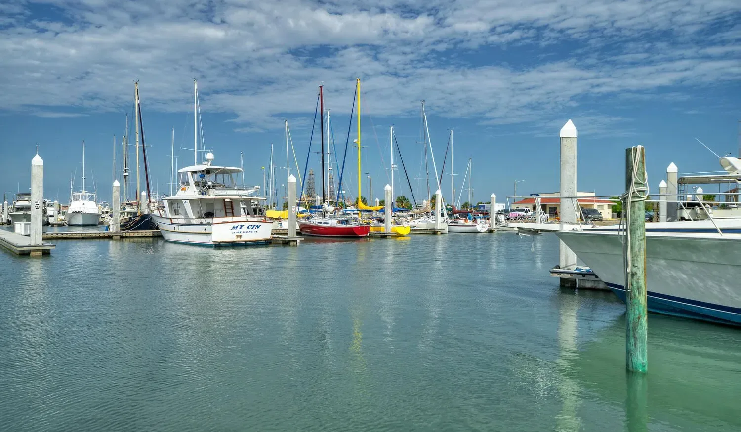 A marina with boats moored along docks under a partly cloudy sky.