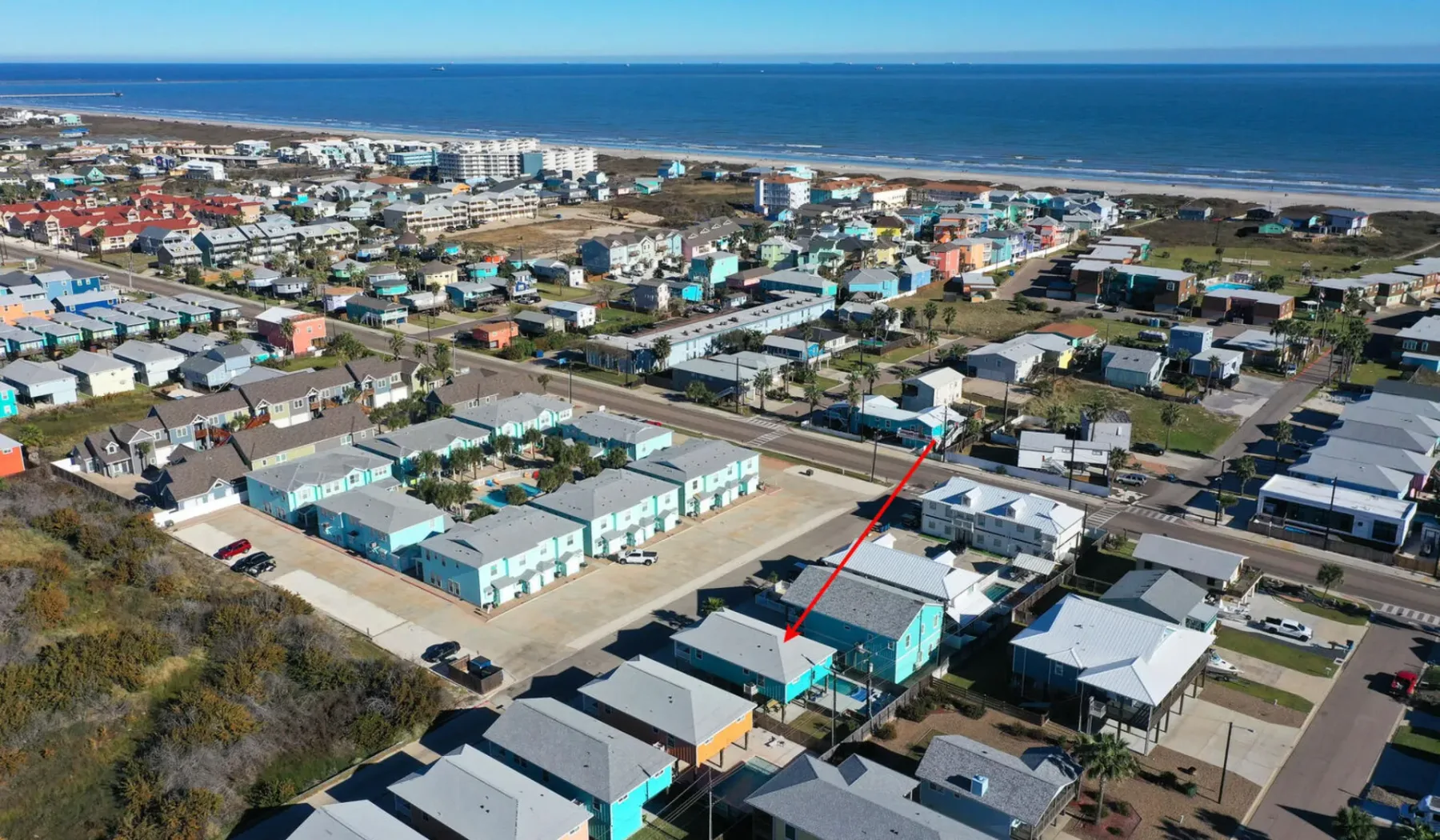 Aerial view of a coastal neighborhood with homes and the ocean beyond.