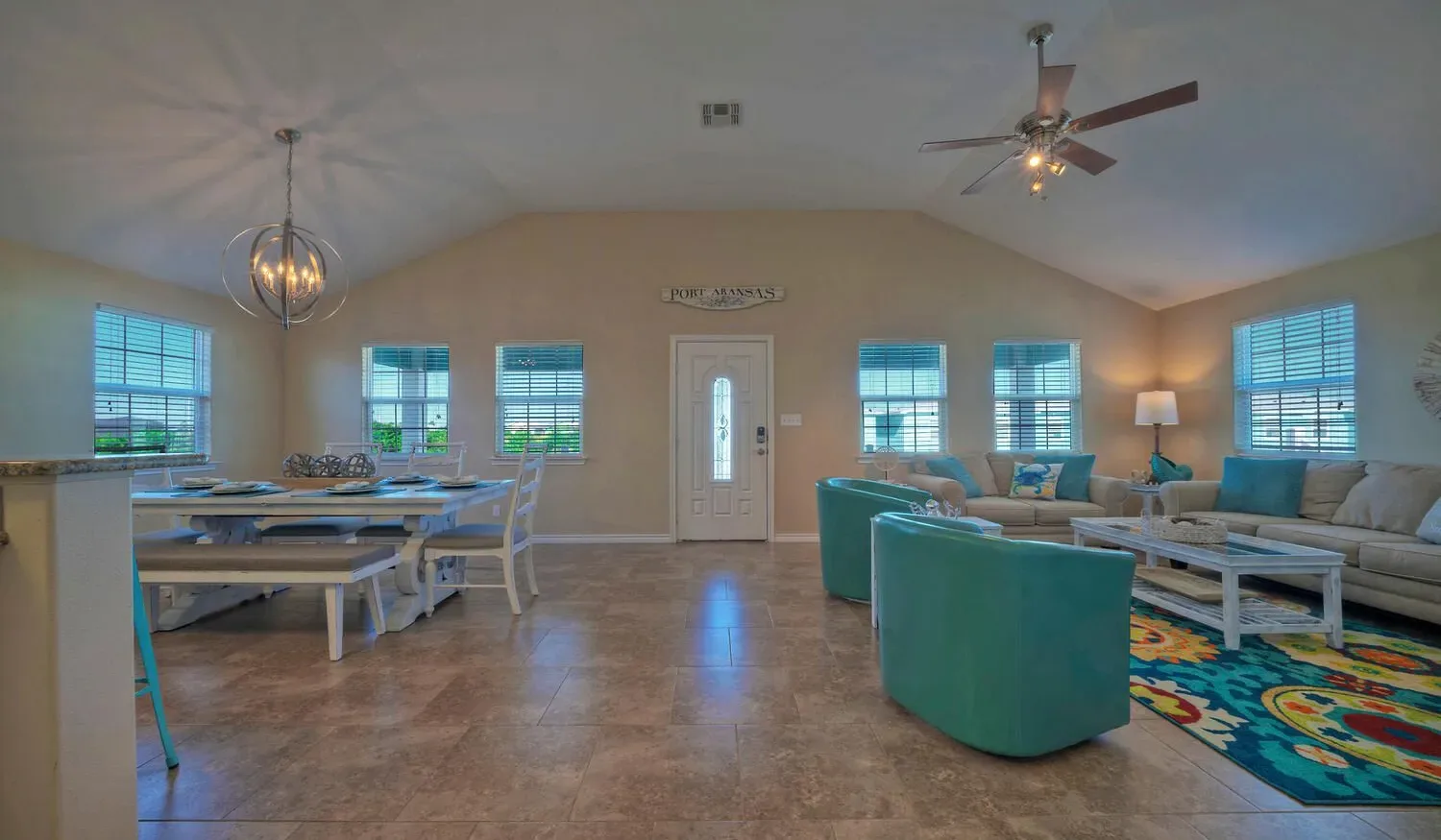 A bright open living and dining area with teal seating and a long dining table.