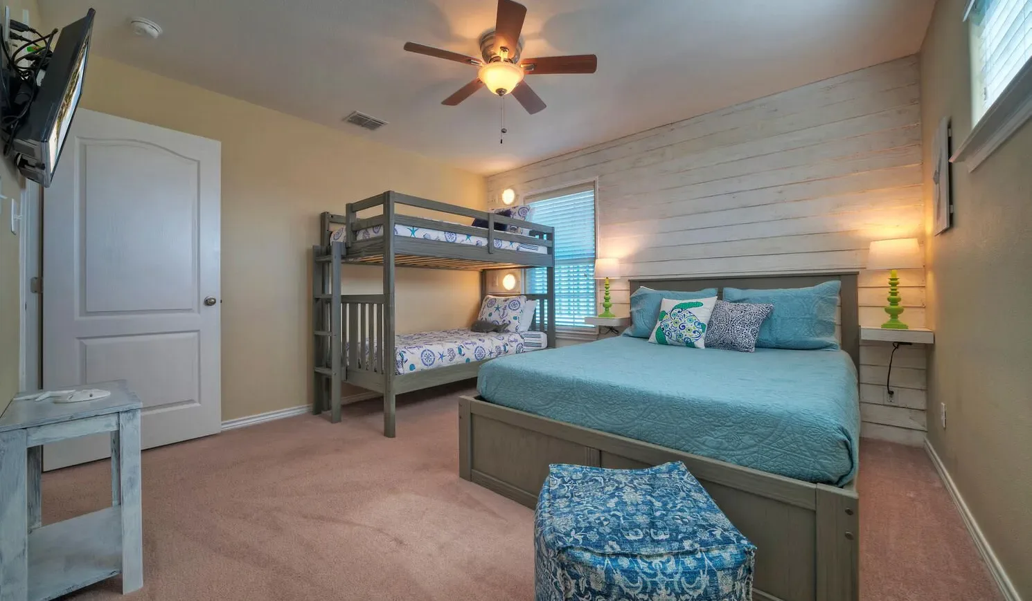 A bedroom with a double bed, bunk beds, and a ceiling fan.